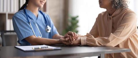 un patient heureux tient le soignant pour une main tout en passant du temps ensemble. femme âgée dans une maison de retraite et infirmière photo