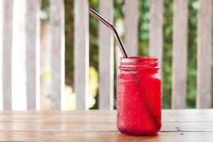 boisson glacée en verre rouge sur une table en bois à l'extérieur