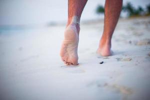 gros plan des jambes masculines sur la plage de sable blanc photo