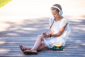 petite fille adorable écoutant de la musique dans le parc photo