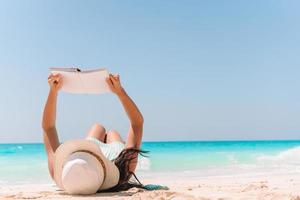 jeune femme lisant un livre sur une chaise longue sur la plage photo