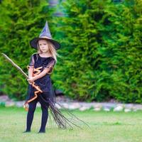 adorable petite fille portant un costume de sorcière à halloween au jour de l'automne. La charité s'il-vous-plaît. photo