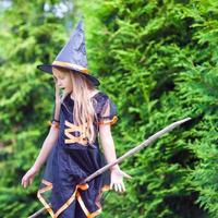 petite fille avec un balai portant un costume de sorcière à halloween. La charité s'il-vous-plaît. photo