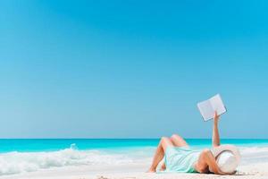 jeune femme lisant un livre pendant une plage blanche tropicale photo