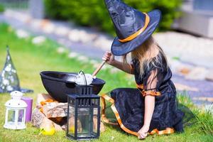 adorable petite fille portant un costume de sorcière jetant un sort à halloween. La charité s'il-vous-plaît. photo