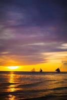 beau coucher de soleil coloré avec voilier à l'horizon sur l'île de boracay photo