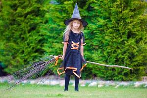 adorable petite fille en costume de sorcière à halloween au jour de l'automne. La charité s'il-vous-plaît. photo