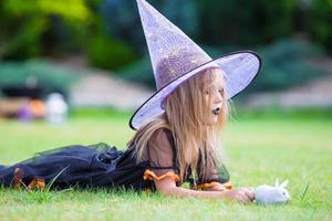 adorable petite fille en costume de sorcière à halloween au jour de l'automne. La charité s'il-vous-plaît. photo