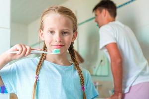 fille heureuse et papa se brosser les dents dans les brosses à dents de la salle de bain photo