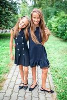 deux jolies petites filles souriantes posant devant leur école. photo