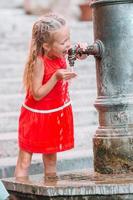 petite fille s'amusant avec de l'eau potable à la fontaine de la rue à rome, italie photo