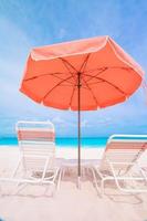 transats et parasols à la plage blanche au bord de la mer photo