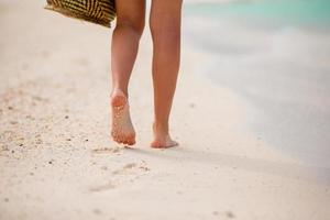 gros plan de pieds féminins sur une plage de sable blanc photo