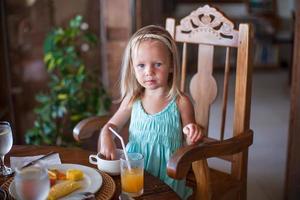 adorable petite fille prenant son petit déjeuner et buvant un cocktail de fruits photo