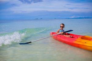 petite fille adorable faisant du kayak dans l'océan bleu clair photo