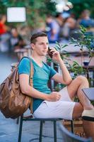 un garçon caucasien tient un téléphone portable à l'extérieur dans la rue. homme utilisant un smartphone mobile. photo