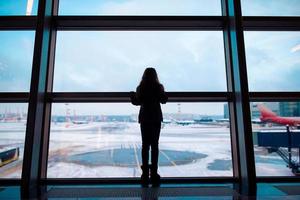 petite fille à l'aéroport près de la grande fenêtre en attendant l'embarquement photo