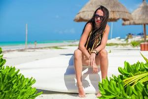 jeune femme sexy assise sur un bateau sur la plage de sable blanc photo