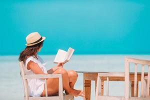 jeune femme lisant un livre pendant une plage blanche tropicale photo