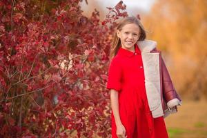 portrait d'une adorable petite fille au bouquet de feuilles jaunes à l'automne photo