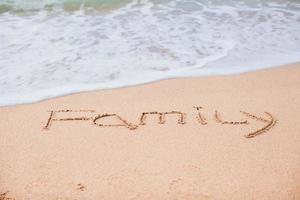 famille dessinant dans le sable sur une plage tropicale photo