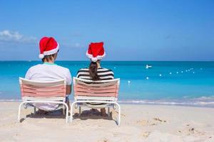 vue arrière du couple en chapeaux santa profiter de vacances à la plage photo