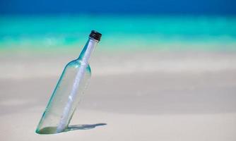 bouteille avec un message enterré dans le sable blanc photo