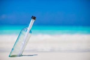 bouteille avec un message enterré dans le sable blanc photo