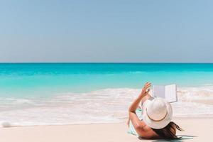 jeune femme lisant un livre sur une chaise longue sur la plage photo