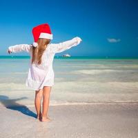 petite fille adorable en bonnet rouge pendant les vacances à la plage tropicale photo