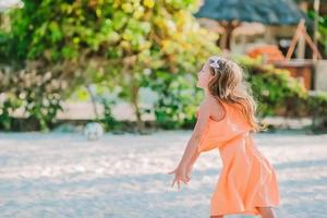 adorable petite fille jouant avec un ballon sur la plage. sports d'été pour enfants en plein air sur l'île des caraïbes photo