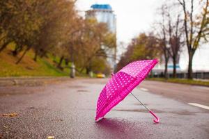 parapluie rose pour enfants sur l'asphalte mouillé à l'extérieur photo