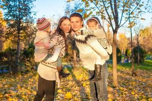 famille de quatre personnes s'amusant dans le parc d'automne par une chaude journée ensoleillée photo