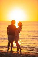 jeune couple passe du temps ensemble sur la plage au coucher du soleil photo