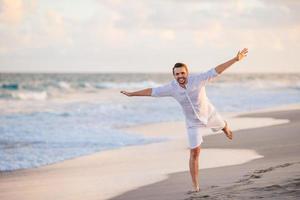 jeune homme en blanc sur la plage s'amusant photo