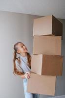 heureuse adorable fille avec des boîtes en carton dans une nouvelle maison le jour du déménagement photo