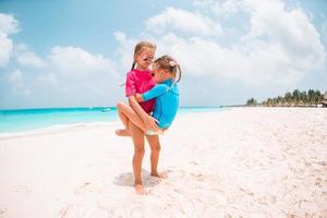 les petites filles drôles et heureuses s'amusent beaucoup sur la plage tropicale en jouant ensemble. photo