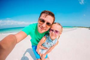 jeune père et petit enfant prenant une photo de selfie sur la plage