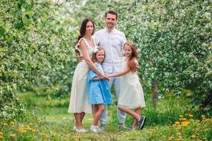 adorable famille dans un jardin de cerisiers en fleurs le beau jour du printemps photo