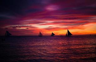 incroyable beau coucher de soleil avec voilier à l'horizon sur l'île de boracay photo