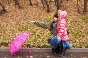 petite fille et sa mère marchant avec un parapluie un jour de pluie photo