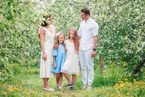 adorable famille dans un jardin de cerisiers en fleurs le beau jour du printemps photo