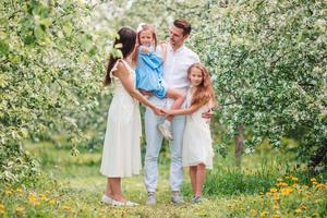 adorable famille dans un jardin de cerisiers en fleurs le beau jour du printemps photo