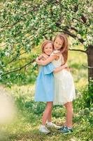 adorables petites filles dans un jardin de pommiers en fleurs le jour du printemps photo