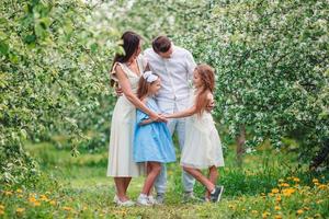 adorable famille dans un jardin de cerisiers en fleurs le beau jour du printemps photo