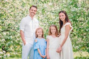 adorable famille dans un jardin de cerisiers en fleurs le beau jour du printemps photo