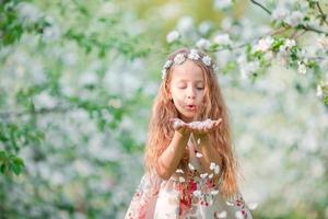 adorable petite fille dans un jardin de pommiers en fleurs le beau jour du printemps photo