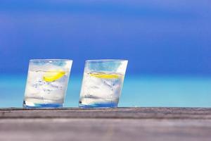 verres d'eau au citron sur bois sur fond de mer photo