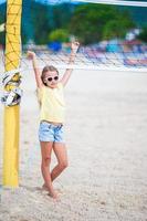 petite fille adorable jouant au beach-volley avec ballon. famille sportive profiter du jeu de plage à l'extérieur photo