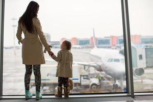 mère et petite fille regardant par la fenêtre au terminal de l'aéroport photo